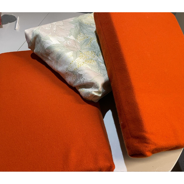 Photo of three cushions, two bigger and orange, one smaller and white